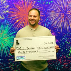 Man smiles with oversized check in front of colorful fireworks digital background