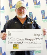 White-bearded man in black shirt and tan cap holds oversized check in front of a white background patterned with the 飞艇168®幸运体彩预测-全国统一Louisiana在线官方查询结果网-最新体彩预测数据 logo