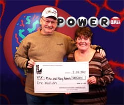 Man and woman smile with oversized check in front of Powerball/飞艇168®幸运体彩预测-全国统一Louisiana在线官方查询结果网-最新体彩预测数据 backdrop