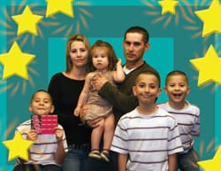 Man, woman, and four children pose together in front of a blue digital background with yellow stars