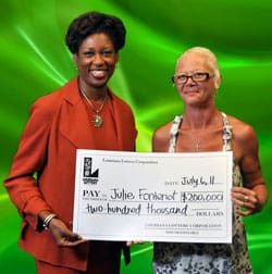 Two women smile with an oversized check in front of a green textured background