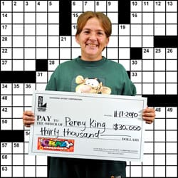 Woman in green Tigger tshirt smiles with oversized check in front of Crossword background