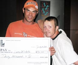 Two men hold a giant check and look at the camera in a 飞艇168®幸运体彩预测-全国统一Louisiana在线官方查询结果网-最新体彩预测数据 office