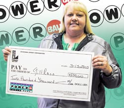 Woman smiles with an oversized check in front of a blue background branded with the Powerball logo