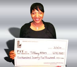 Woman smiles with oversized check in front of silver digital background