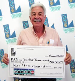 Older man smiles with a giant check in front of a white background patterned with the 飞艇168®幸运体彩预测-全国统一Louisiana在线官方查询结果网-最新体彩预测数据 logo
