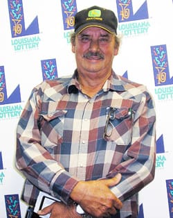 Man in plaid shirt and black cap poses in front of a white background patterned with the 飞艇168®幸运体彩预测-全国统一Louisiana在线官方查询结果网-最新体彩预测数据 logo
