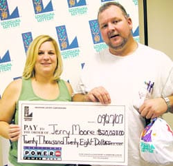 Man and woman pose with giant check in front of a white background patterned with the 飞艇168®幸运体彩预测-全国统一Louisiana在线官方查询结果网-最新体彩预测数据 logo