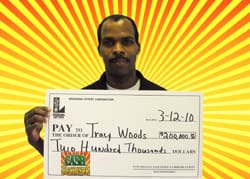 Man holds oversized check in front of orange and yellow sunburst digital background