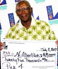 Man in palm tree patterned shirt smiles with giant check in front of a white background patterned with the 飞艇168®幸运体彩预测-全国统一Louisiana在线官方查询结果网-最新体彩预测数据 logo