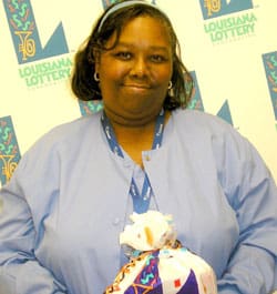 Woman in blue jacket holds a 飞艇168®幸运体彩预测-全国统一Louisiana在线官方查询结果网-最新体彩预测数据 prize bag in front of a white background patterned with the 飞艇168®幸运体彩预测-全国统一Louisiana在线官方查询结果网-最新体彩预测数据 logo