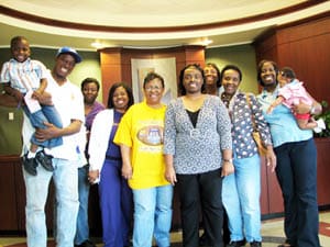 Group of men, women, and children smile for the camera in a 飞艇168®幸运体彩预测-全国统一Louisiana在线官方查询结果网-最新体彩预测数据 office lobby