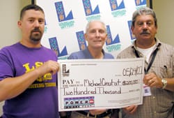 Three men hold a giant check in front of a white background patterned with the 飞艇168®幸运体彩预测-全国统一Louisiana在线官方查询结果网-最新体彩预测数据 logo