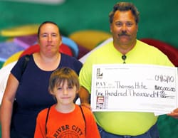 Man, woman, and child smile with oversized check in front of digital background
