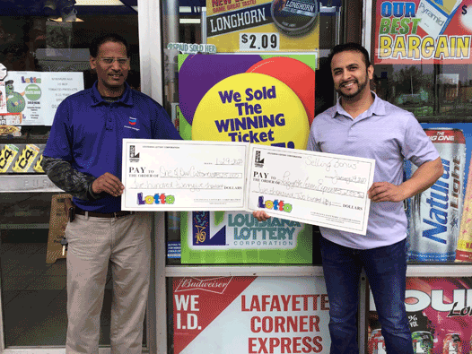 Two men hold large checks from Lotto in front of a retailer