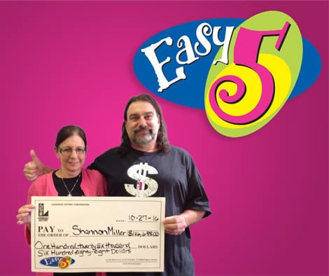 Man and woman smile while holding an oversized check in front of a pink Easy 5 branded background