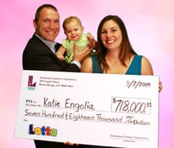 Man, woman, and baby pose with an oversized check in front of a pink digital background