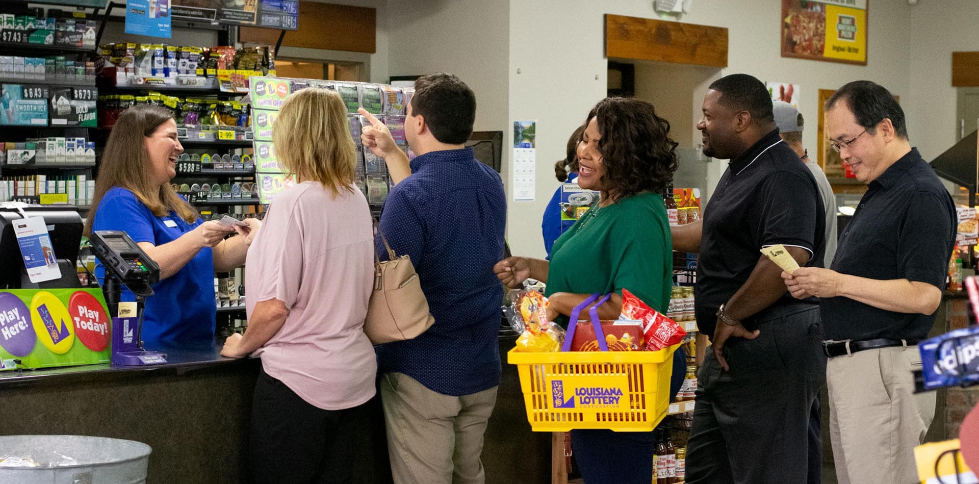 People in line at a retailer, happily waiting to check out with their Lottery purchases, as a female cashier laughs with customers