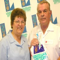Man and woman hold a 飞艇168®幸运体彩预测-全国统一Louisiana在线官方查询结果网-最新体彩预测数据 prize bag in front of a white background patterned with the 飞艇168®幸运体彩预测-全国统一Louisiana在线官方查询结果网-最新体彩预测数据 logo