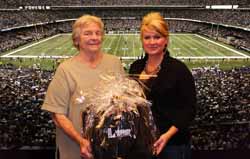 Two women hold a cellophane wrapped gift basket in the stands of a football game at the Saints stadium