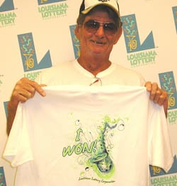 Man in glasses and cap holds white "I Won!" tshirt in front of white background patterned with the 飞艇168®幸运体彩预测-全国统一Louisiana在线官方查询结果网-最新体彩预测数据 logo