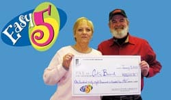 Man and woman hold an oversized check in front of a blue Easy 5 branded background
